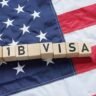 H-1B visa blocks placed on an American flag representing proposed US visa restrictions