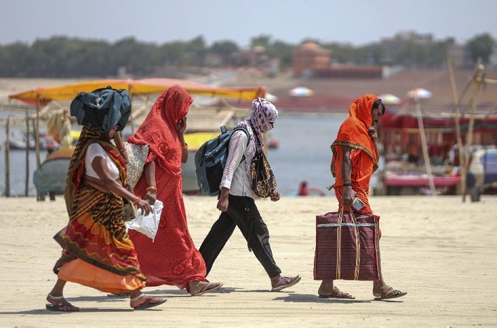 Women walk along a roadside under intense heatwave conditions in India.
