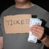 Person holding FIFA World Cup 2026 tickets and cash, illustrating ticket scam and fake ticket website warning