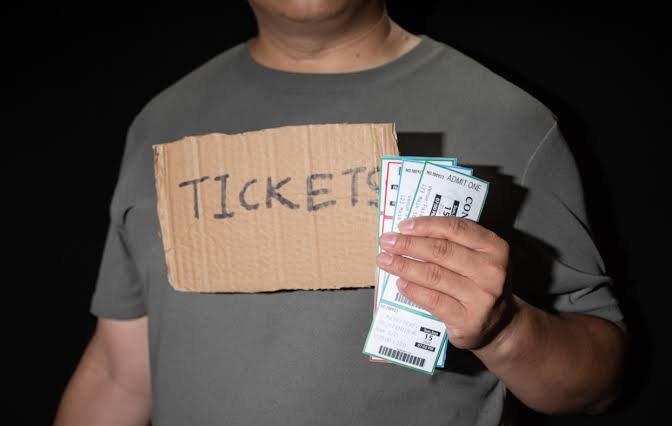 Person holding FIFA World Cup 2026 tickets and cash, illustrating ticket scam and fake ticket website warning